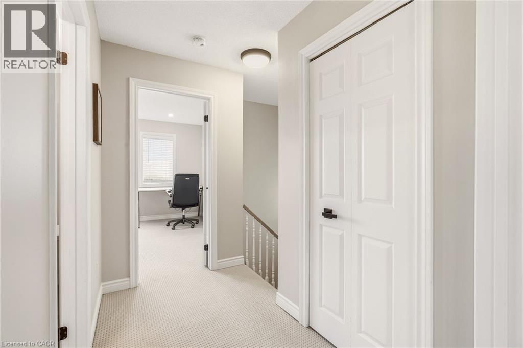 Well-lit hallway featuring light-colored carpet flooring, white trim, and a contemporary ceiling light fixture - 1 Tomahawk Drive, Grimsby, ON - Indoor