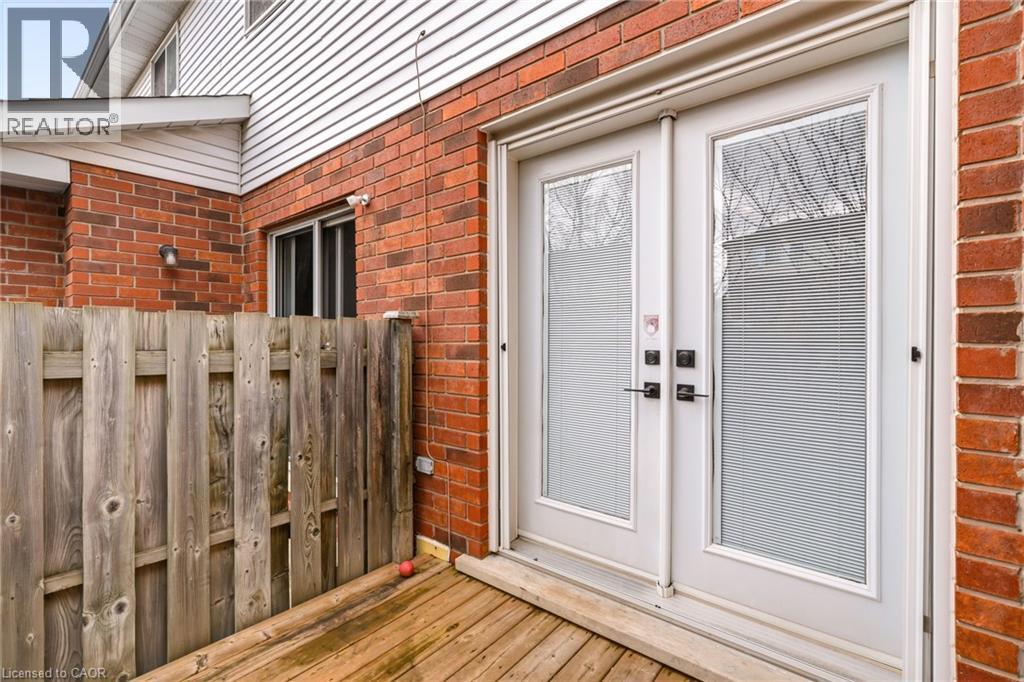 The property features a brick exterior with white siding, a wooden fence, and a wooden deck - 1 Tomahawk Drive, Grimsby, ON - Outdoor With Deck Patio Veranda With Exterior
