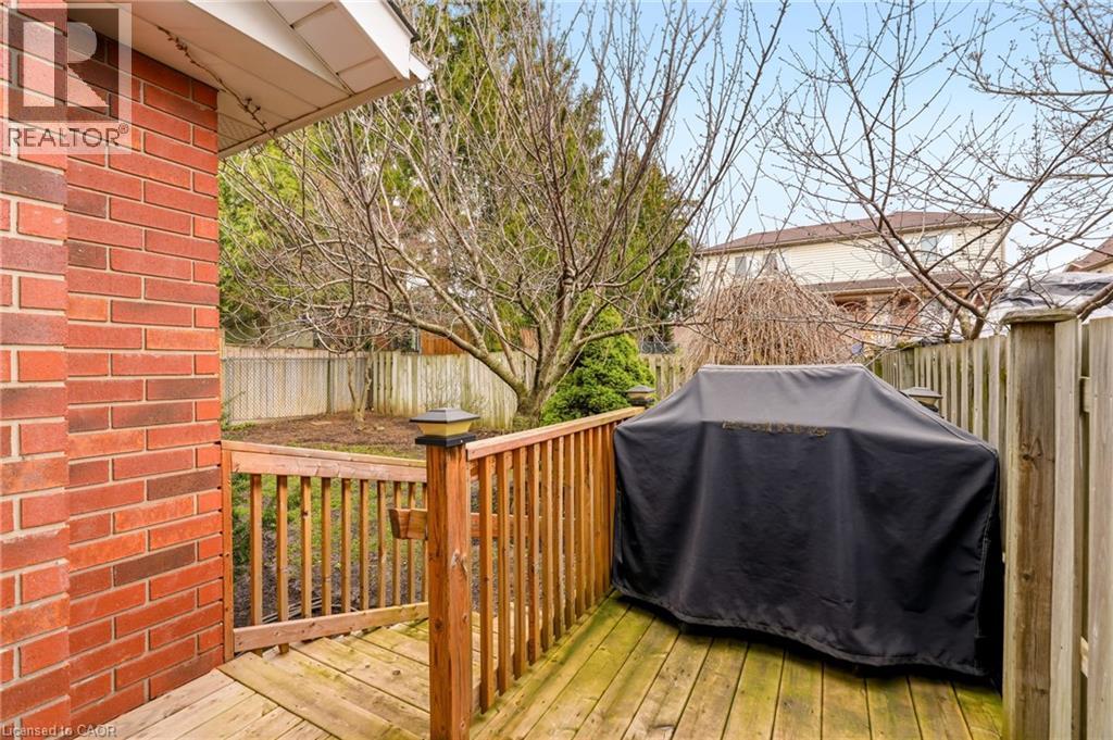 The property features a wood deck with a railing, a red brick exterior, and a fenced yard with mature trees - 1 Tomahawk Drive, Grimsby, ON - Outdoor With Deck Patio Veranda With Exterior