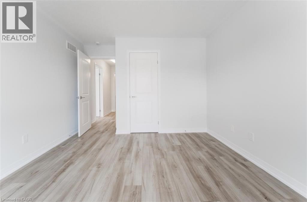 This room features light-colored laminate flooring, white walls, and white baseboards - 686 Benninger Drive, Kitchener, ON - Indoor Photo Showing Other Room