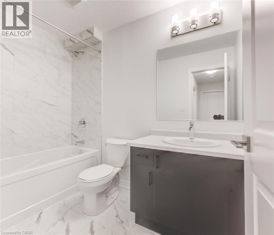 Bathroom featuring a white bathtub, a toilet, and a vanity with a white countertop and a dark base - 686 Benninger Drive, Kitchener, ON - Indoor Photo Showing Bathroom