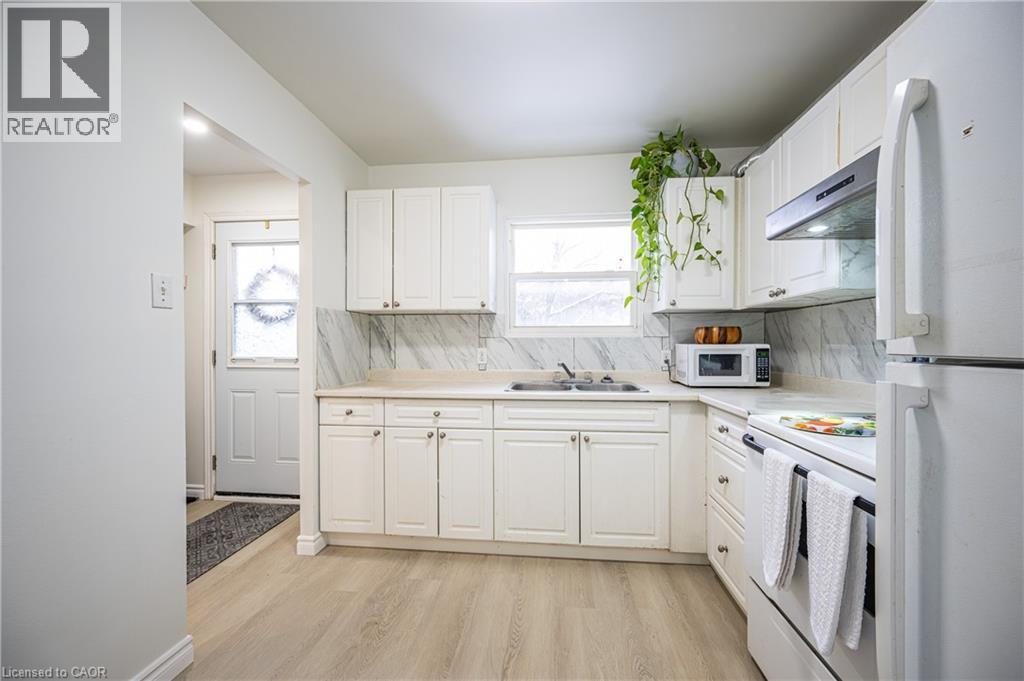 The kitchen features light-toned flooring, white cabinetry, and a white countertop - 212 Westcourt Place, Waterloo, ON - Indoor Photo Showing Kitchen With Double Sink