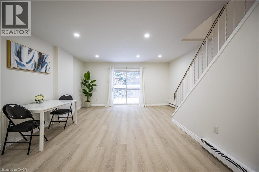 The property features light-toned flooring, a staircase with white railings, and a sliding glass door providing natural light - 212 Westcourt Place, Waterloo, ON - Indoor Photo Showing Other Room