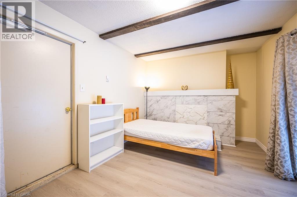This room features a white ceiling with exposed wooden beams, light-colored flooring, and a decorative wall with a marbled tile pattern - 212 Westcourt Place, Waterloo, ON - Indoor Photo Showing Bedroom