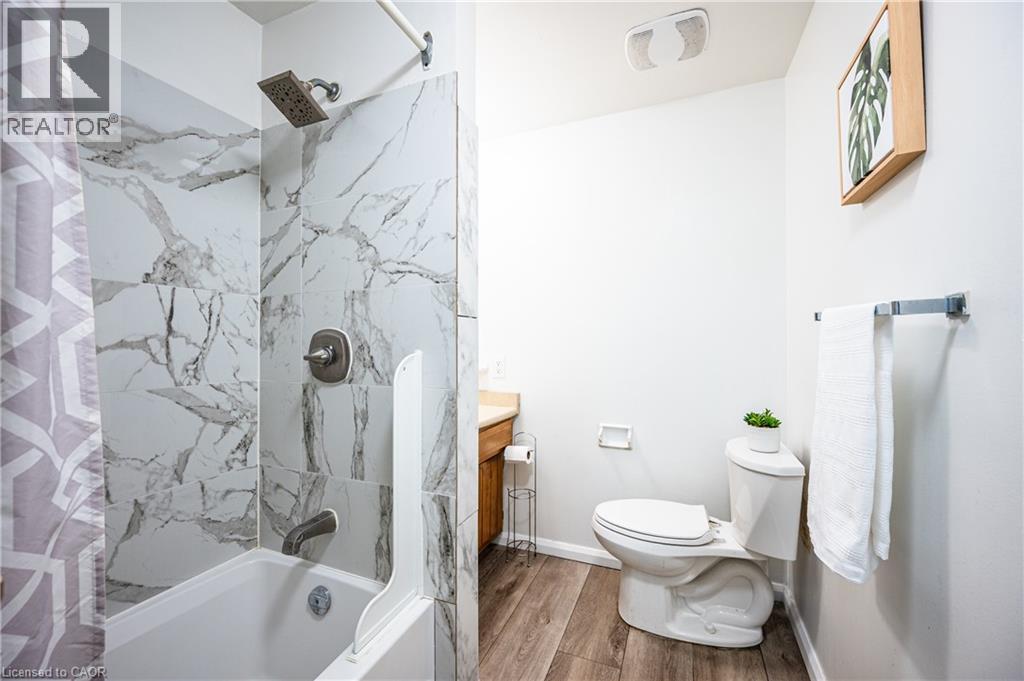 Bathroom featuring a white bathtub with marble-look tile surround and a rain showerhead - 212 Westcourt Place, Waterloo, ON