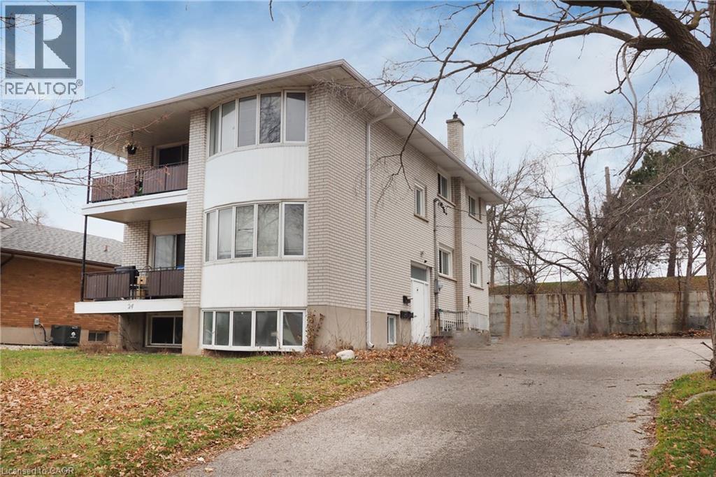 The property features a multi-level structure with light-colored brick siding and prominent bay windows - 24 Austin Drive, Waterloo, ON - Outdoor