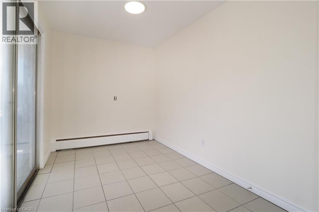 This bright space features tile flooring, baseboard heating, a ceiling light fixture, and a sliding glass door - 24 Austin Drive, Waterloo, ON - Indoor Photo Showing Other Room