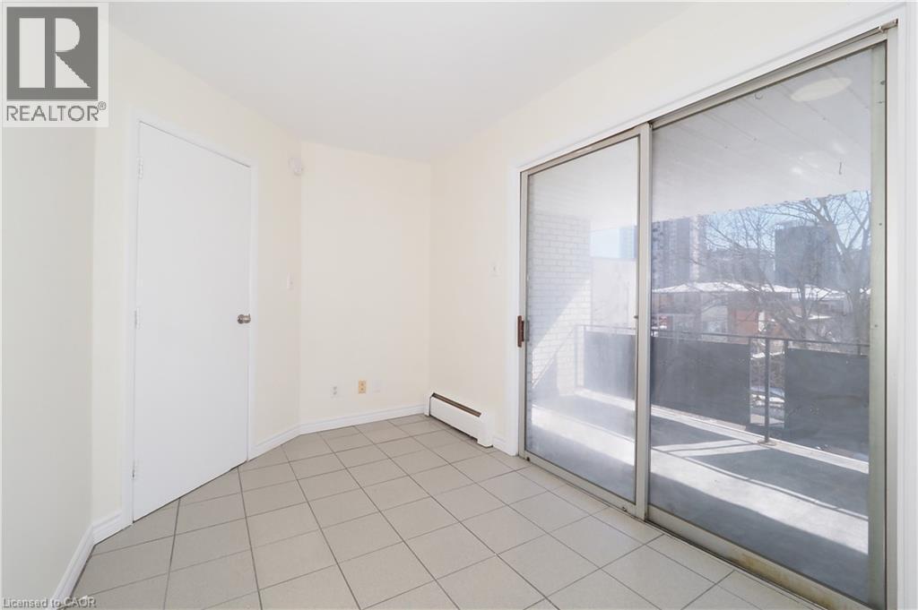 This room features light-colored tile flooring, a white door, and a sliding glass door leading to a balcony - 24 Austin Drive, Waterloo, ON - Indoor Photo Showing Other Room