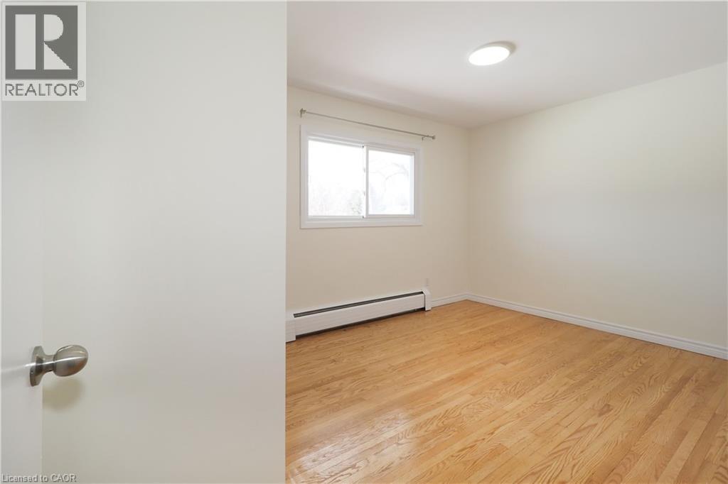 This room features hardwood flooring, a window providing natural light, and a ceiling-mounted light fixture - 24 Austin Drive, Waterloo, ON - Indoor Photo Showing Other Room