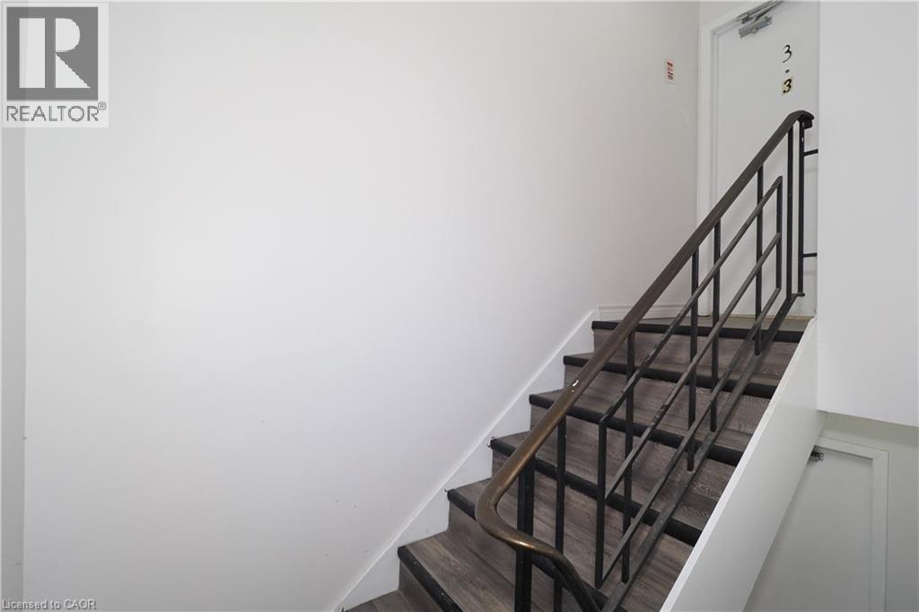 Stairway featuring wood-look treads, white risers, and a dark-toned metal handrail - 24 Austin Drive, Waterloo, ON - Indoor Photo Showing Other Room