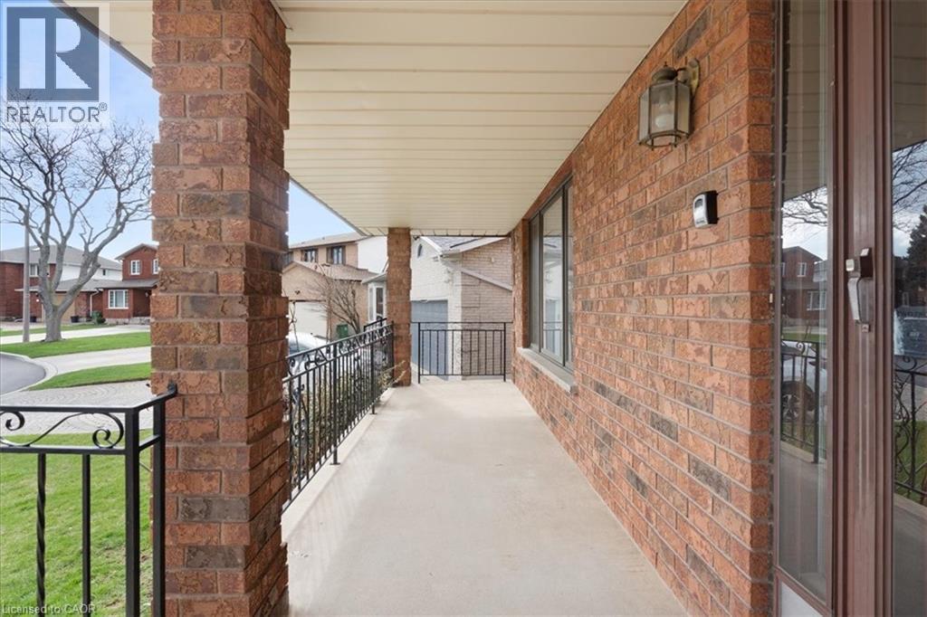 The property features a brick exterior with a covered porch, complete with decorative metal railings, and an exterior light fixture - 18 Marcel Place, Hamilton, ON - Outdoor With Exterior