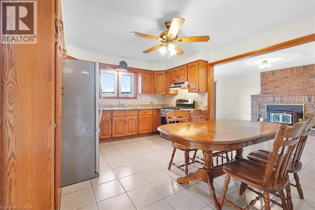 The kitchen features ample wood cabinetry, a ceiling fan, and tiled flooring - 18 Marcel Place, Hamilton, ON - Indoor Photo Showing Dining Room With Fireplace