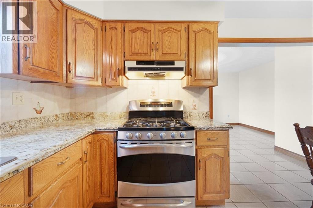 The kitchen features light wood cabinetry, stone countertops, and a stainless steel range with an overhead vent - 18 Marcel Place, Hamilton, ON - Indoor Photo Showing Kitchen