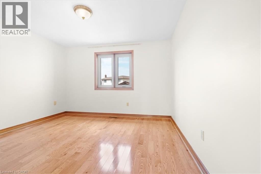 The property features a room with hardwood flooring, light-colored walls, and a window with a brown frame - 18 Marcel Place, Hamilton, ON - Indoor Photo Showing Other Room