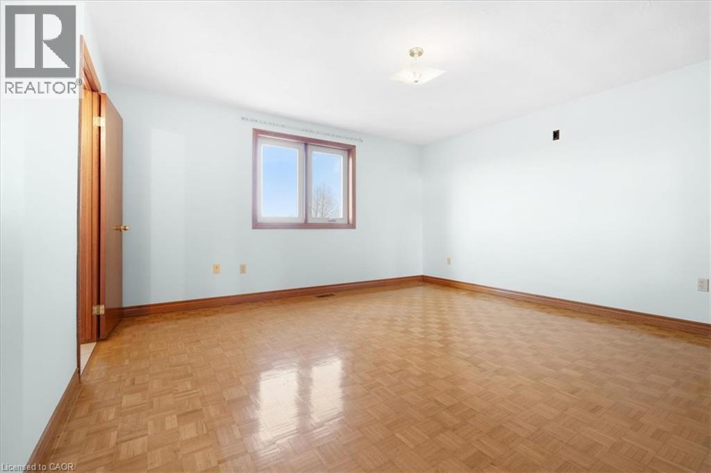This room features hardwood flooring, light blue walls, and a window with a brown frame - 18 Marcel Place, Hamilton, ON - Indoor Photo Showing Other Room