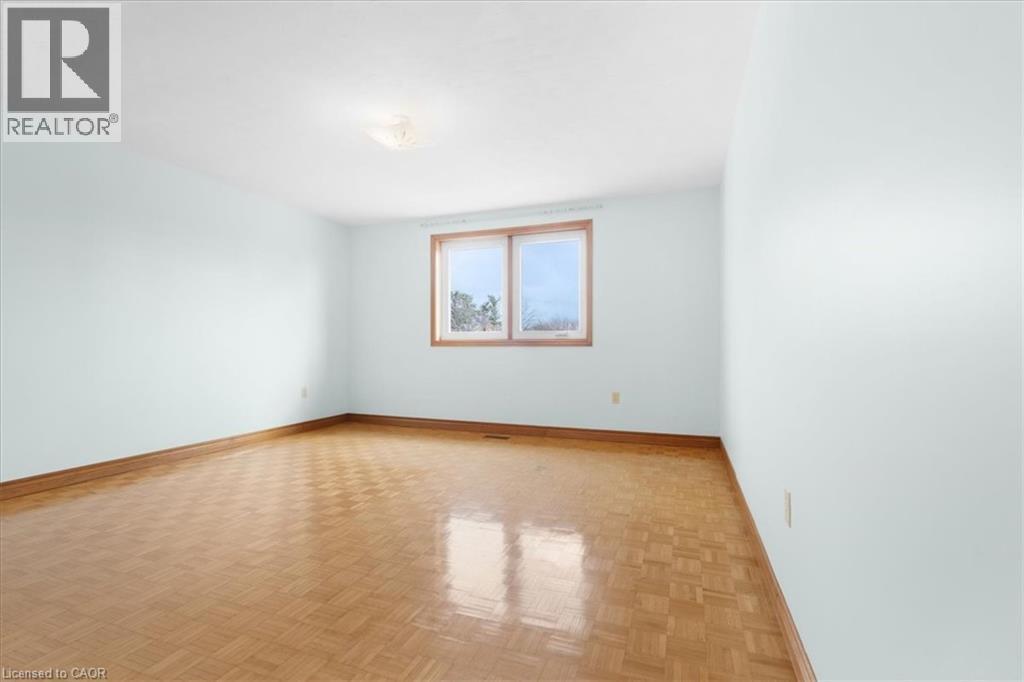This room features light blue walls, wood flooring, and a window with a wood frame - 18 Marcel Place, Hamilton, ON - Indoor Photo Showing Other Room