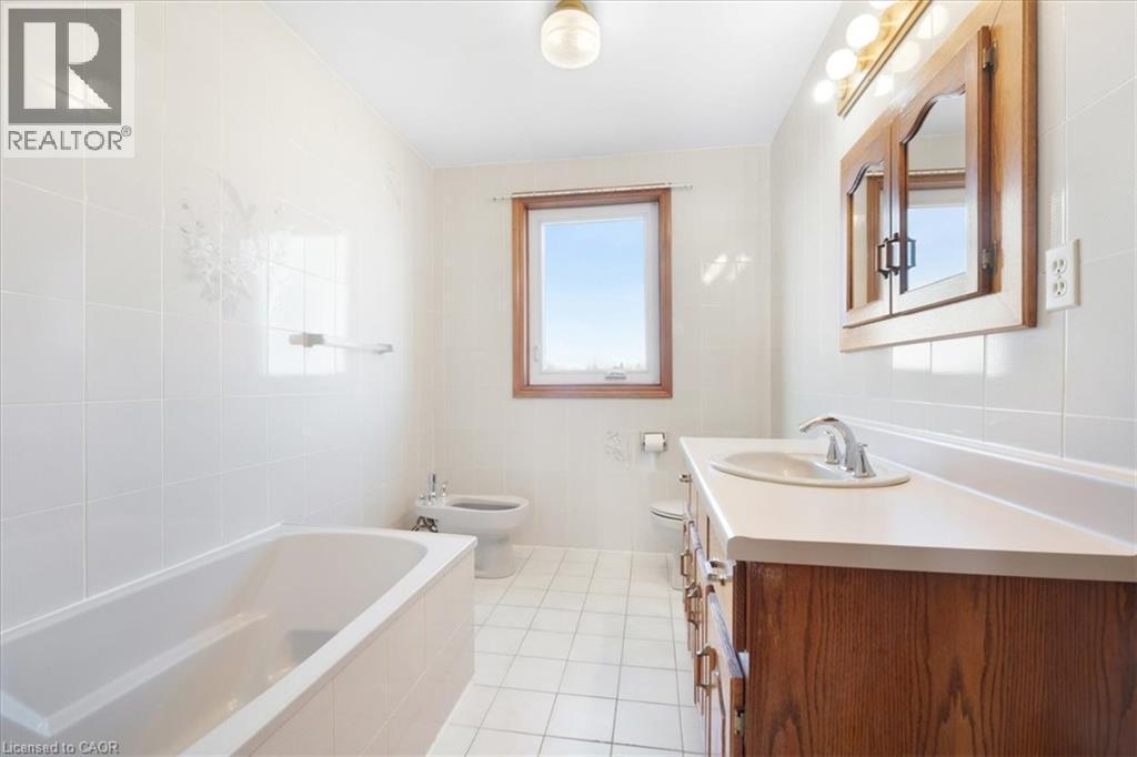Well-appointed bathroom featuring a bathtub, a window, a vanity with a sink, and a mirrored medicine cabinet - 18 Marcel Place, Hamilton, ON - Indoor Photo Showing Bathroom
