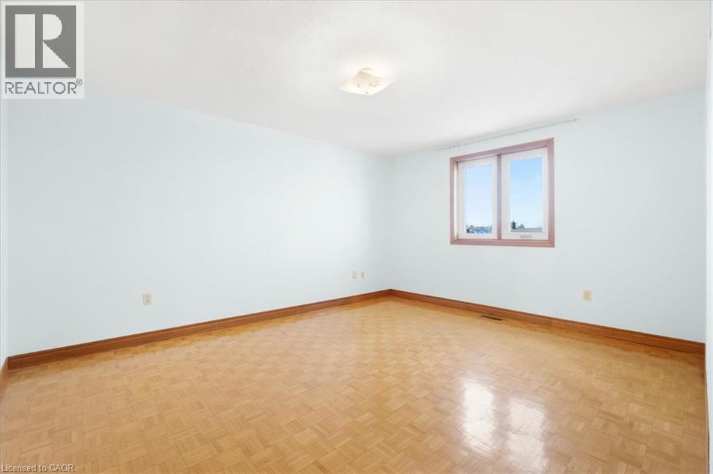 Room featuring light blue walls, wood parquet flooring, and a window providing natural light - 18 Marcel Place, Hamilton, ON - Indoor Photo Showing Other Room