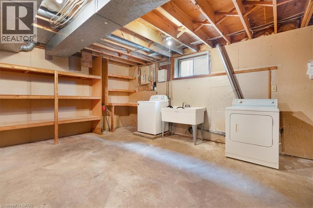 The property includes a utility area with exposed ceiling joists, a laundry sink, and a washer and dryer - 18 Marcel Place, Hamilton, ON - Indoor Photo Showing Laundry Room