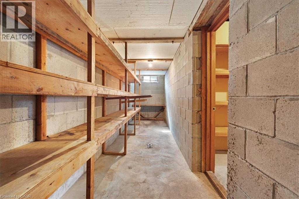 The property features extensive wooden shelving units, concrete block walls, and a concrete floor - 18 Marcel Place, Hamilton, ON - Indoor Photo Showing Other Room