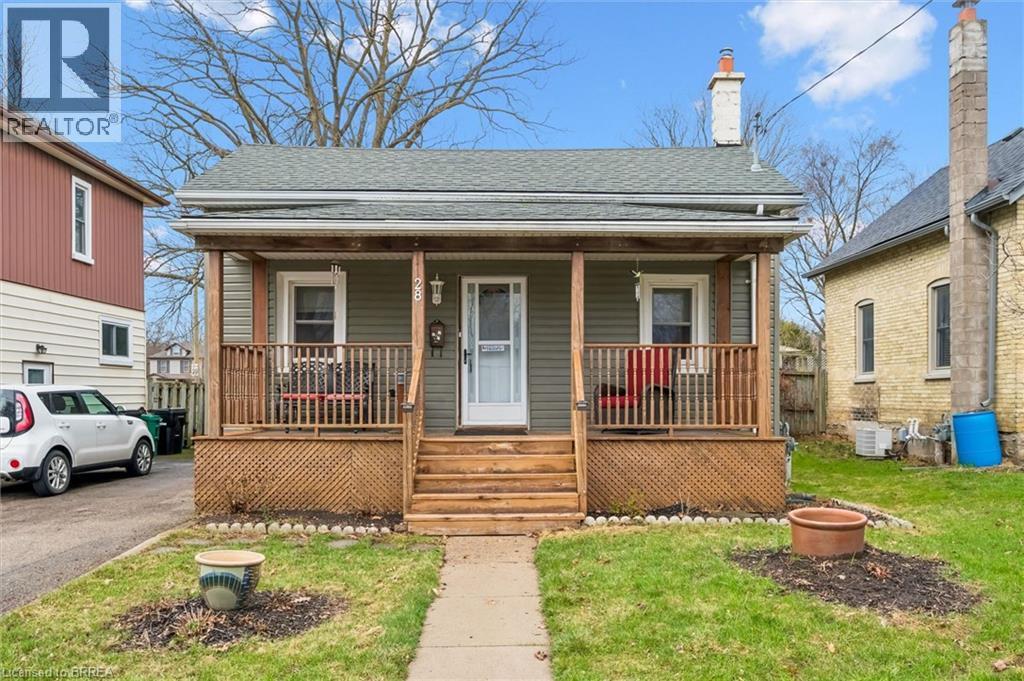The property features a charming front porch with wood railings and steps, set against a light green siding exterior - 28 Davidson Street, Cambridge, ON - Outdoor With Deck Patio Veranda