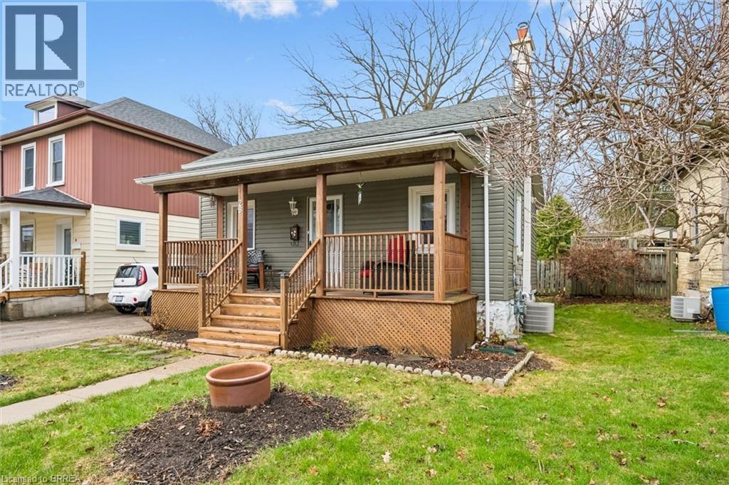 The property features a charming front porch with wooden railings and steps, set on a grassy yard with a concrete pathway leading to the entrance - 28 Davidson Street, Cambridge, ON - Outdoor With Deck Patio Veranda