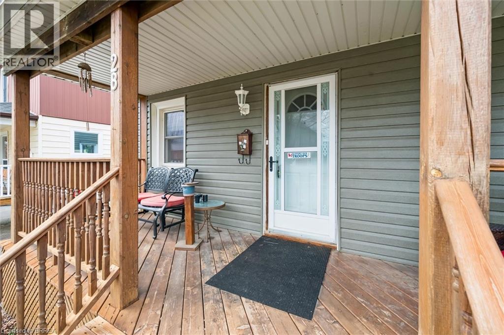The property features a front porch with natural wood decking and railings, complemented by green horizontal siding - 28 Davidson Street, Cambridge, ON - Outdoor With Deck Patio Veranda With Exterior
