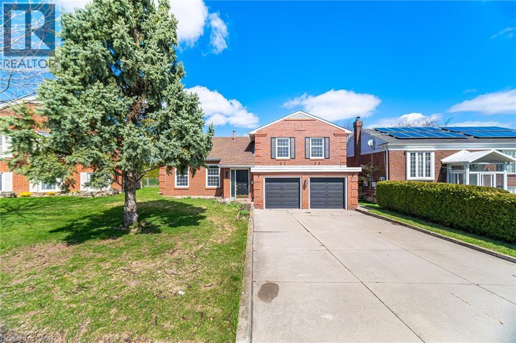 The property features a brick facade, a two-car garage, and a paved driveway - 38 Leclaire Street, Hamilton, ON - Outdoor