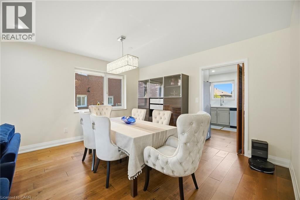 This dining area features hardwood floors and a modern rectangular chandelier - 38 Leclaire Street, Hamilton, ON - Indoor Photo Showing Dining Room