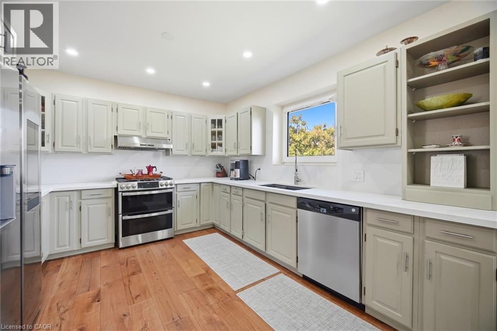 The kitchen features hardwood floors, light-colored cabinetry, white countertops, and stainless steel appliances - 38 Leclaire Street, Hamilton, ON - Indoor Photo Showing Kitchen With Stainless Steel Kitchen