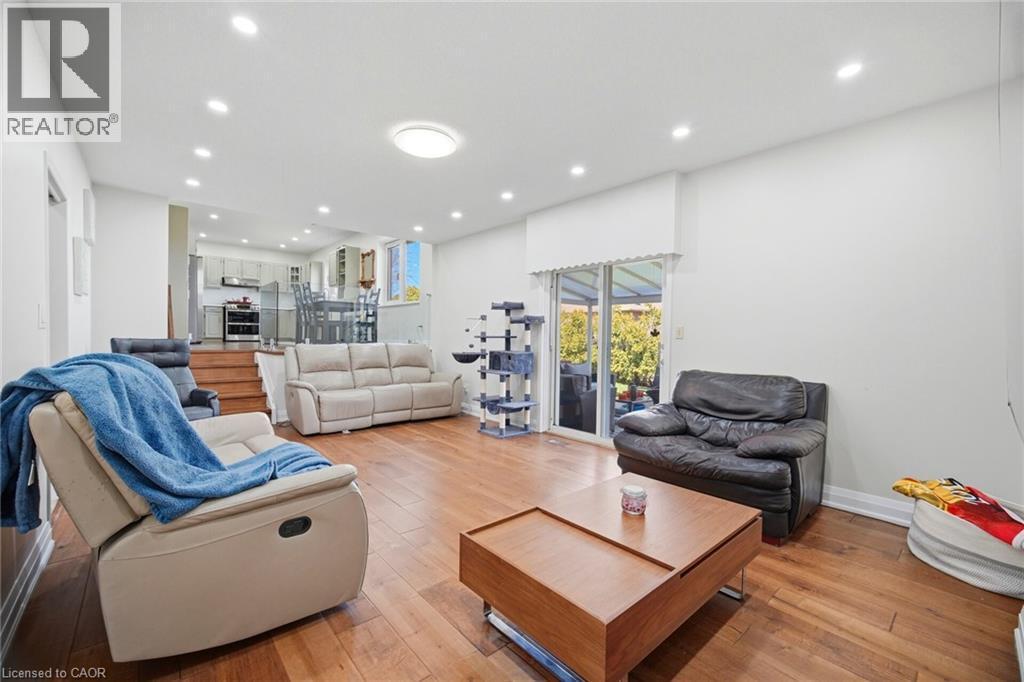 Spacious living area featuring warm wood flooring and recessed lighting, with sliding glass doors providing access to the outdoors - 38 Leclaire Street, Hamilton, ON - Indoor Photo Showing Living Room