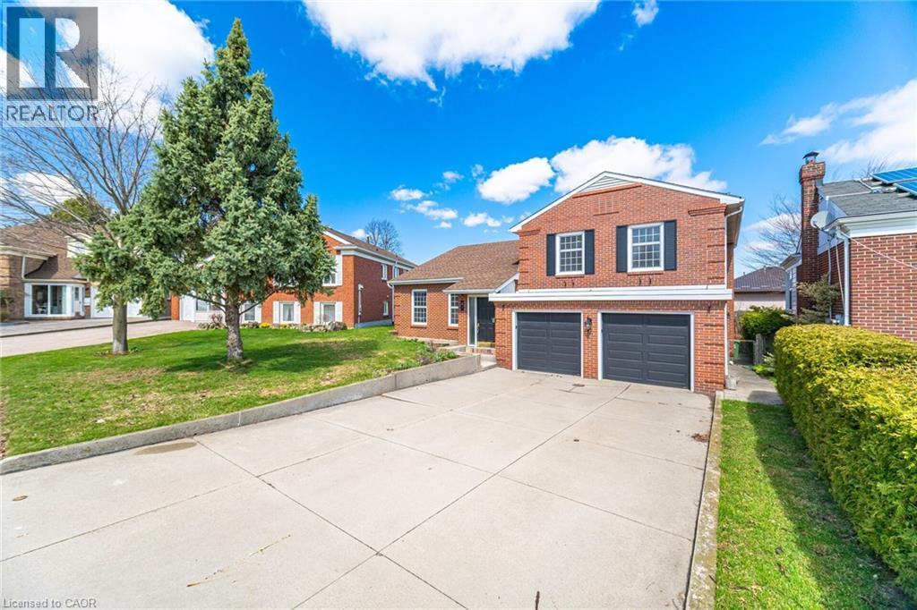 The property features a brick exterior, a two-car garage, and a concrete driveway - 38 Leclaire Street, Hamilton, ON - Outdoor With Facade