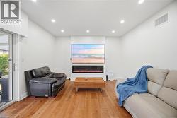 The living space features hardwood floors, recessed lighting, and a prominent media wall with an integrated electric fireplace -