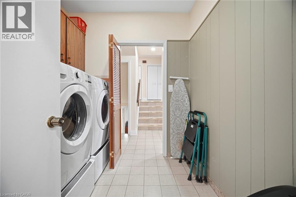 The property features a dedicated laundry area with white appliances and a tiled floor - 38 Leclaire Street, Hamilton, ON - Indoor Photo Showing Laundry Room