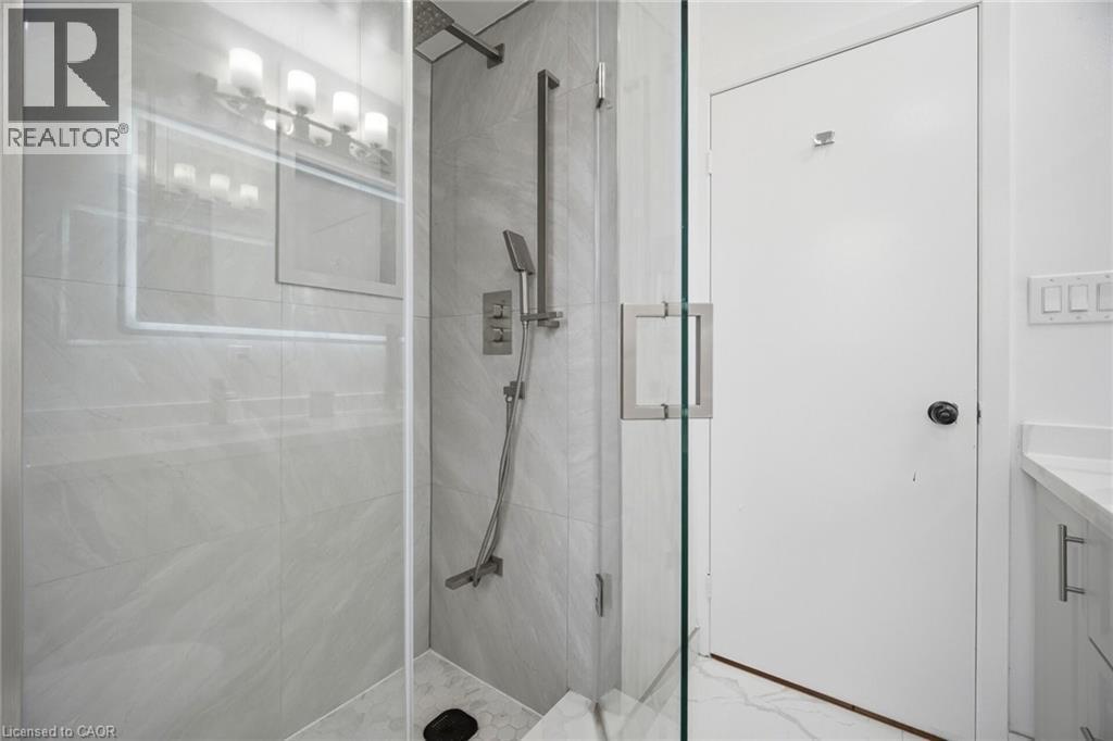 Modern shower with glass enclosure, light-colored tiled walls, and brushed nickel fixtures - 38 Leclaire Street, Hamilton, ON - Indoor Photo Showing Bathroom