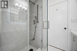 Modern shower with glass enclosure, light-colored tiled walls, and brushed nickel fixtures -
