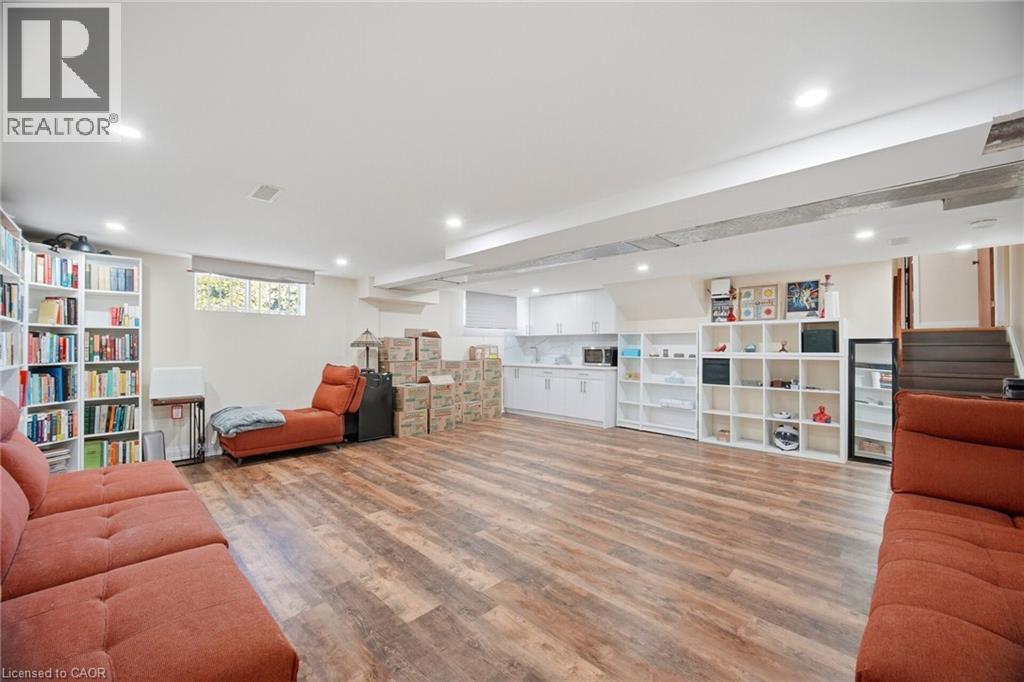 Expansive interior space featuring wood-style flooring, recessed lighting, and a white kitchen area with countertops and cabinetry - 38 Leclaire Street, Hamilton, ON - Indoor