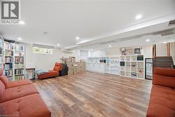 Expansive interior space featuring wood-style flooring, recessed lighting, and a white kitchen area with countertops and cabinetry -