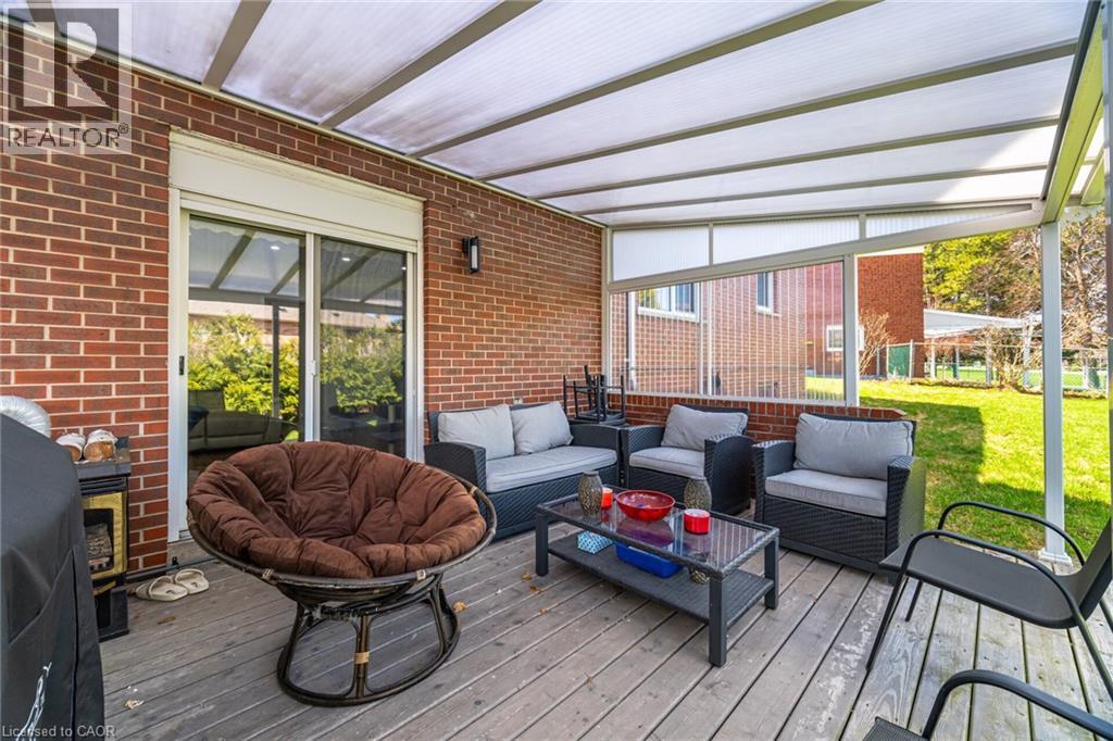 The property features a covered patio with a wooden deck, brick exterior walls, and a sliding glass door providing direct access to the interior - 38 Leclaire Street, Hamilton, ON - Outdoor With Deck Patio Veranda With Exterior