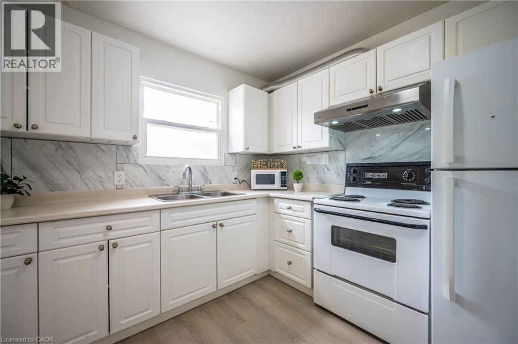 Bright kitchen featuring white cabinetry, a double basin sink, and a light-toned countertop - 212 Westcourt Place, Waterloo, ON - Indoor Photo Showing Kitchen With Double Sink