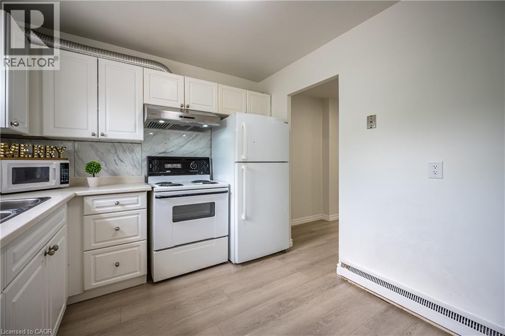 Kitchen featuring white cabinetry, a light-toned countertop, and a patterned backsplash - 212 Westcourt Place, Waterloo, ON - Indoor Photo Showing Kitchen