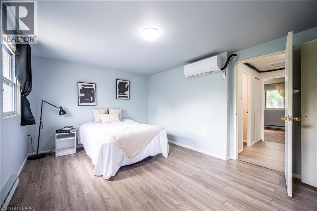 Bright room featuring wood-finish flooring and a single window with dark drapery - 212 Westcourt Place, Waterloo, ON - Indoor Photo Showing Bedroom