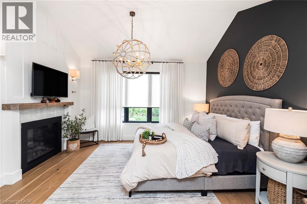 Bedroom featuring a vaulted ceiling with exposed beam-look detailing and a prominent fireplace with a rustic wood mantel - 253 Central Avenue, Grimsby, ON