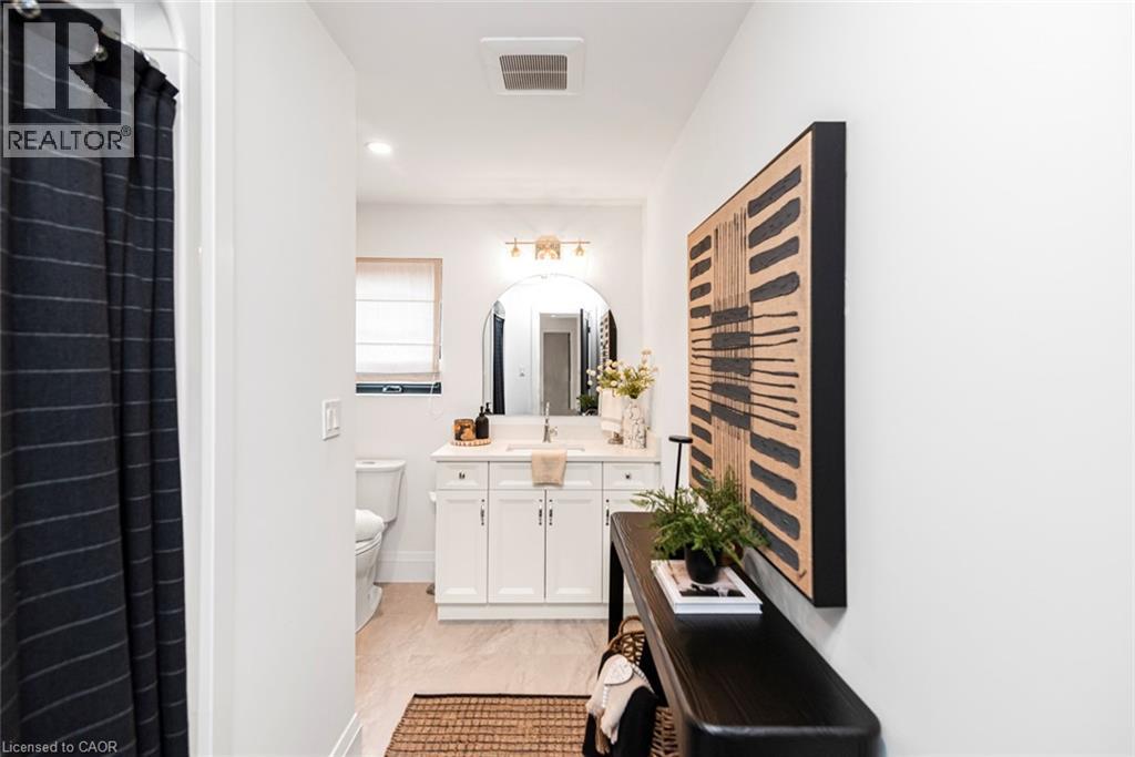 Contemporary bathroom vanity with a single basin sink, white cabinetry, and a rectangular mirror - 253 Central Avenue, Grimsby, ON