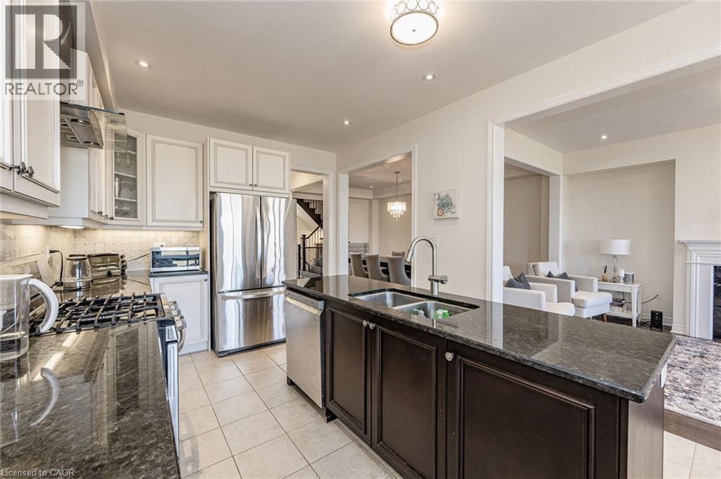 Well-appointed kitchen featuring a large island with an undermount sink, stainless steel appliances, white cabinetry, and dark granite countertops - 2453 Village Common, Oakville, ON - Indoor Photo Showing Kitchen With Stainless Steel Kitchen With Double Sink With Upgraded Kitchen