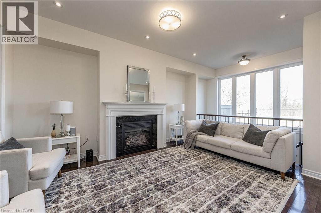 This living area features rich hardwood flooring, a fireplace with a white mantel, and recessed lighting - 2453 Village Common, Oakville, ON - Indoor Photo Showing Living Room With Fireplace