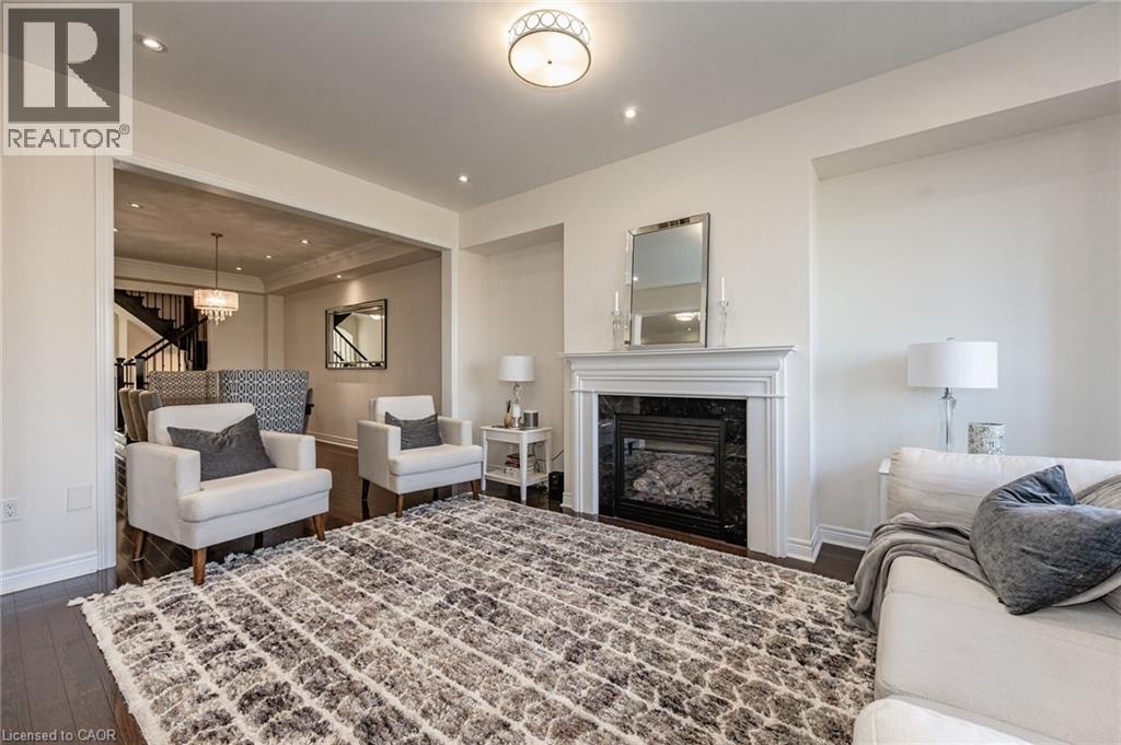 The living area features a decorative ceiling light fixture, recessed lighting, and dark hardwood floors - 2453 Village Common, Oakville, ON - Indoor Photo Showing Living Room With Fireplace