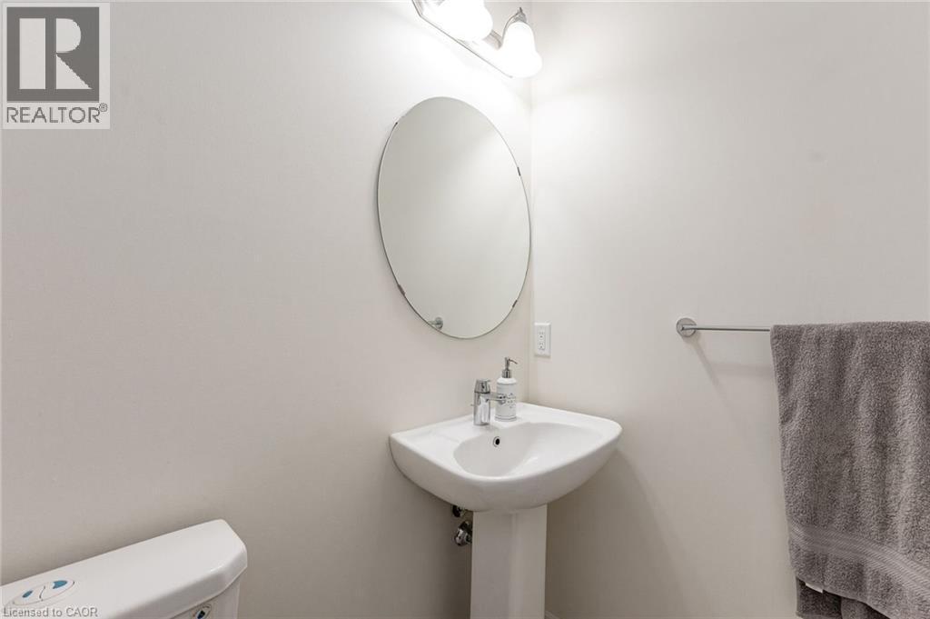 Well-appointed bathroom featuring a pedestal sink, an oval mirror, and overhead lighting - 2453 Village Common, Oakville, ON - Indoor Photo Showing Bathroom