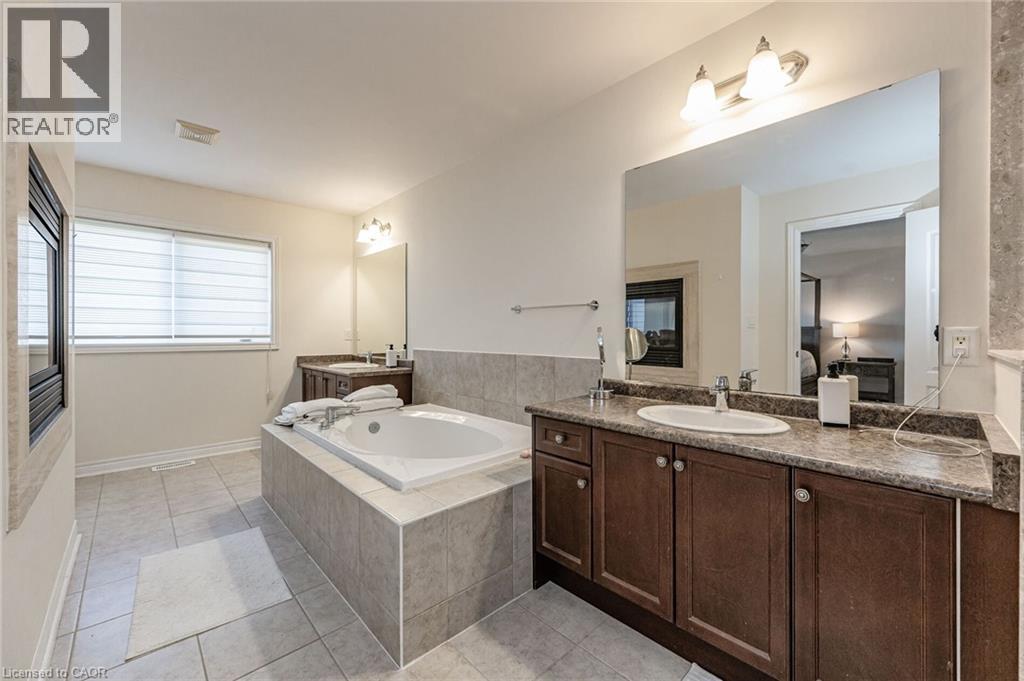 The bathroom features a built-in bathtub, a window with blinds, and tiled flooring - 2453 Village Common, Oakville, ON - Indoor Photo Showing Bathroom