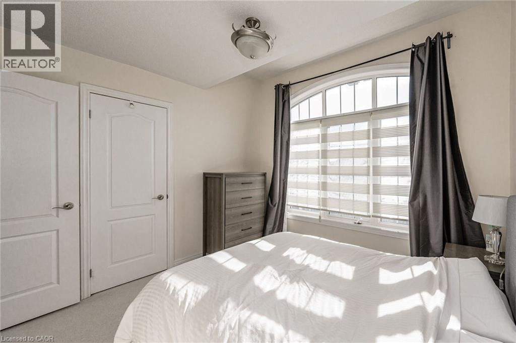 The property features an arched window with blinds and drapes, two panel doors, and a ceiling light fixture - 2453 Village Common, Oakville, ON - Indoor Photo Showing Bedroom
